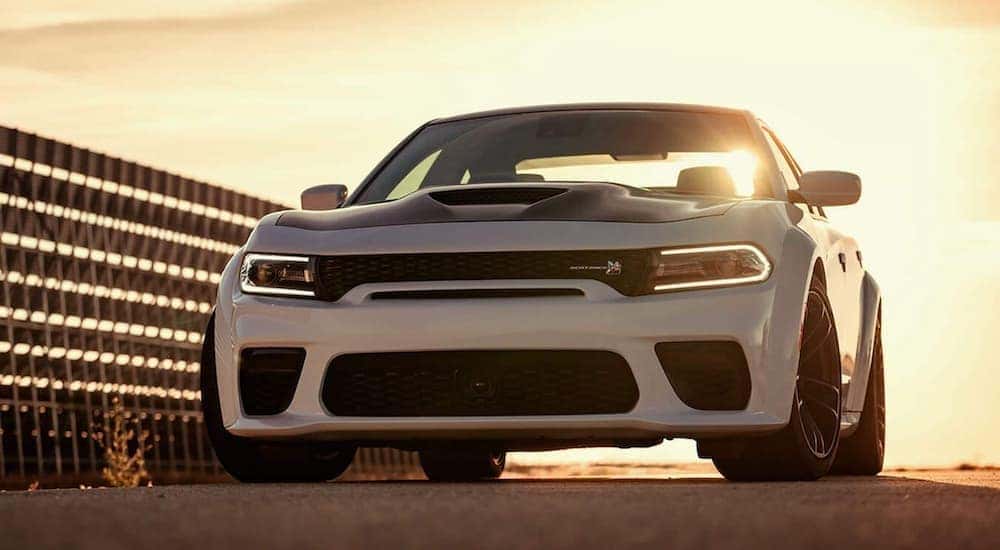 A white 2021 Dodge Charger is shown from the front parked at sunset.