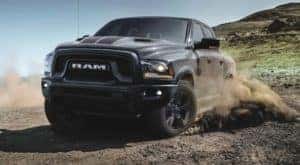 A grey 2020 Ram 1500 Classic Warlock is shown kicking up dust after leaving a Certified Pre-Owned Ram dealer.