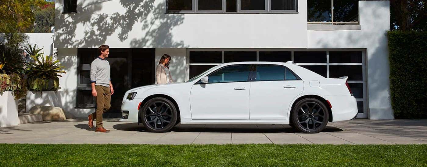 A white 2020 Chrysler 300 is shown on front of a modern house after visiting a Certified Pre-Owned c…