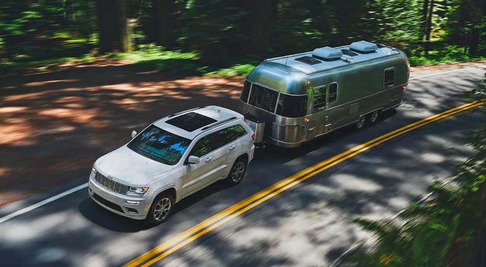 A white 2020 Jeep Grand Cherokee is shown from a high angle towing an Airstream trailer.