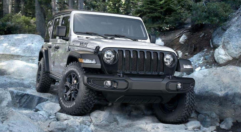 A grey 2020 Jeep Wrangler Willys Unlimited is shown crawling over rocks after visiting a Certified Pre-Owned car dealership.