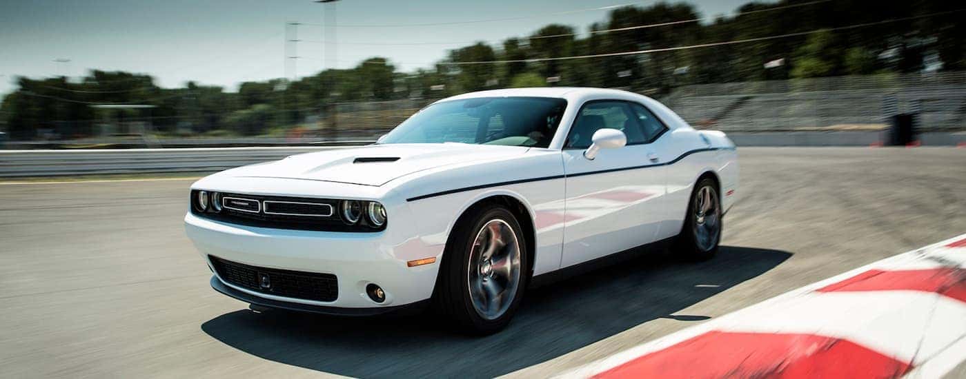 A white 2015 Dodge Challenger is shown driving on a race track.