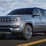A silver 2022 Grand Wagoneer is shown from the front driving on an open road after leaving a Cincinnati Grand Wagoneer dealer.