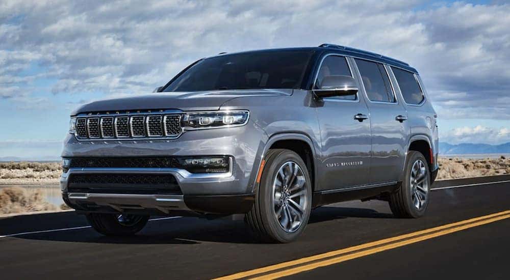 A silver 2022 Grand Wagoneer is shown from the front driving on an open road after leaving a Cincinnati Grand Wagoneer dealer.