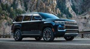 A black 2022 Grand Wagoneer is shown from the side parked in front of a mountain.