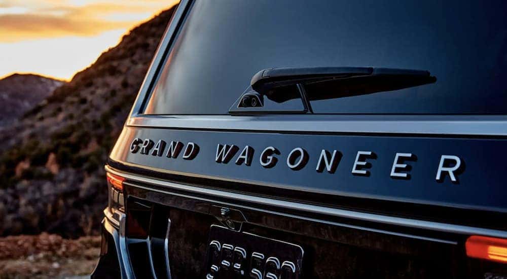 A black 2022 Grand Wagoneer is shown from the rear driving on an open road.