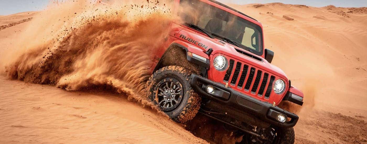 A red 2022 Jeep Wrangler is shown from the front off-roading in the desert.
