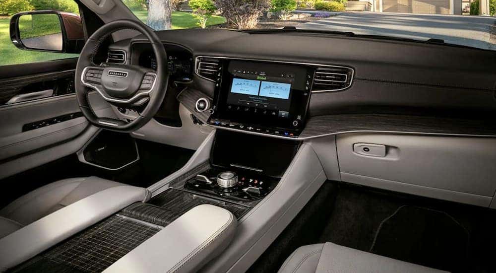 The black and grey interior of a 2022 Wagoneer shows the steering wheel and infotainment screen.