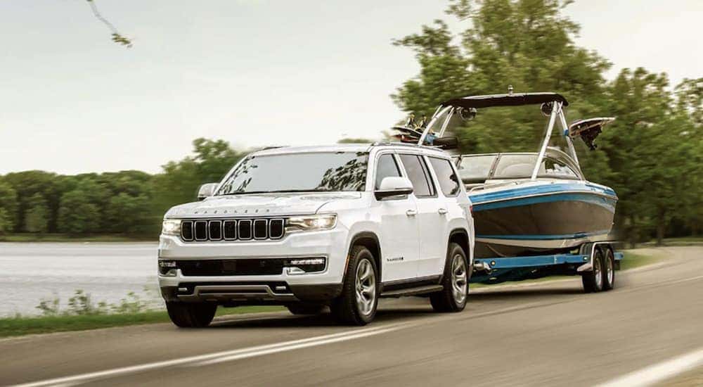 A white 2022 Wagoneer is shown towing a boat past a lake.