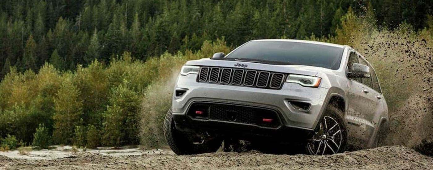 A grey 2019 Jeep Grand Cherokee is shown from the front off-roading after leaving a Cincinnati used…