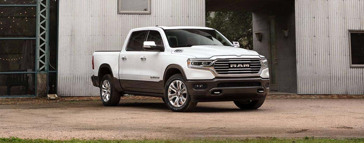 A white 2020 Ram 1500 Longhorn is shown from the front parked in front of a modern building.