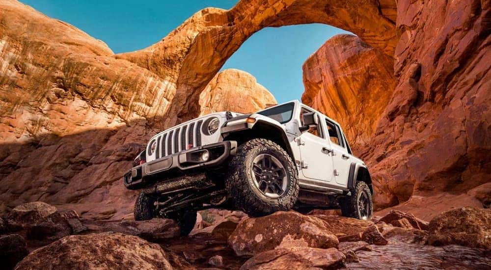 A 2022 Jeep Wrangler Rubicon is shown from the front at a low angle while parked on red rocks after the owner read the Wranglers buyer guide.
