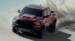 A red 2022 Ram TRX is shown from the front off-roading in the desert.