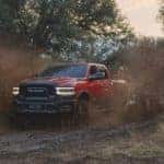 A red 2022 Ram 2500 Power Wagon is shown driving through mud after leaving a Ram Dealer in Cincinnati.