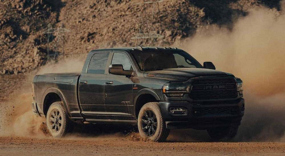 A black 2022 Ram 2500 is shown from the front while kicking up dirt.
