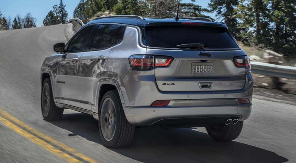 A silver 2022 Jeep Compass is shown from the rear driving on an open road.
