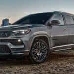 A grey 2022 Jeep Compass is shown from the side parked outside of a city.