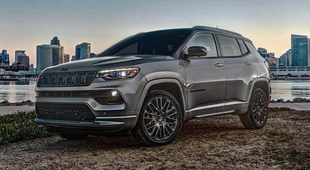 A grey 2022 Jeep Compass is shown from the side parked outside of a city.