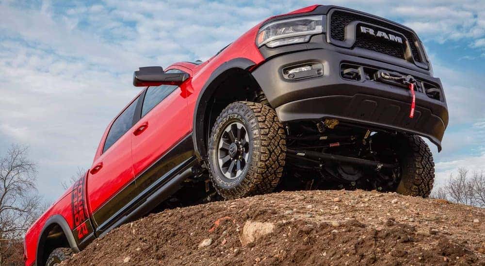 A red 2022 Ram 2500 Power Wagon is shown fro the front at a low angle while it crawls over a rock.