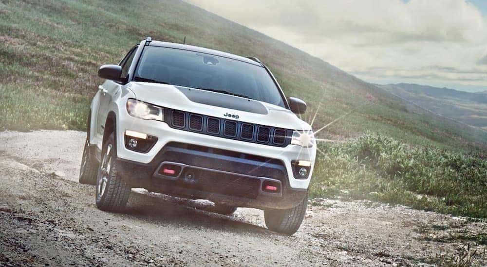 A white 2022 Jeep Compass Trailhawk is shown from the front on a trail after leaving a Jeep Compass dealer.