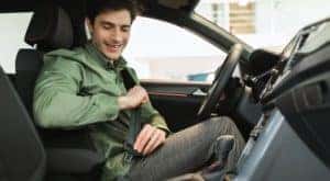 A person is shown buckling into the front seat of a car.