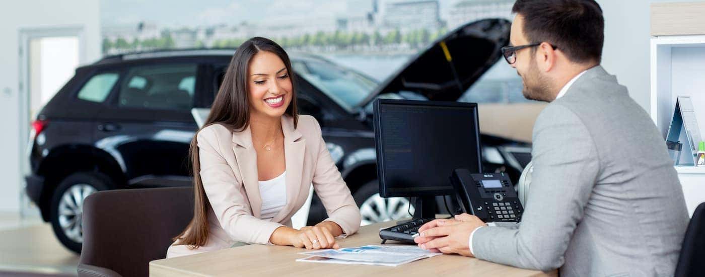 A person is shown talking to a salesperson about selling their car.