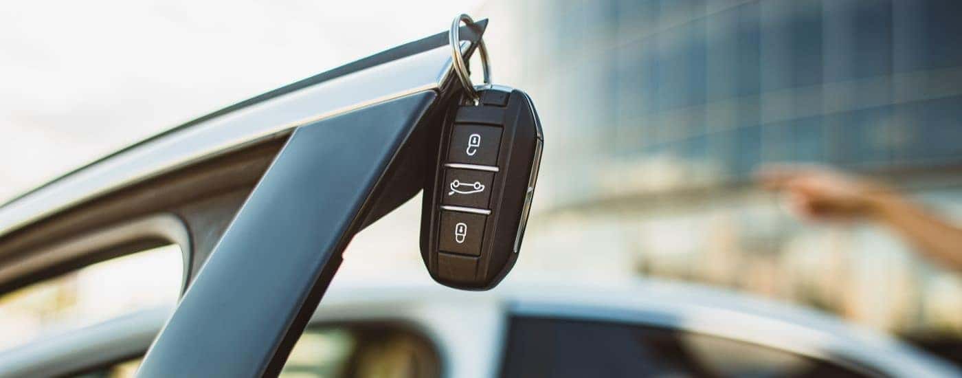 A key fob is shown hanging on a vehicle door.