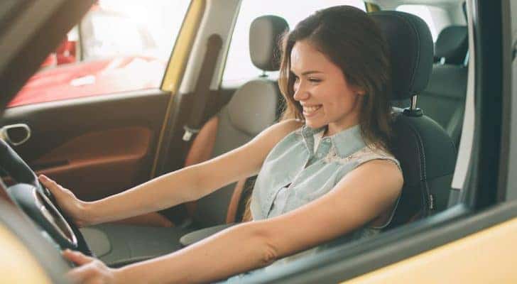 A person is shown sitting in the front seat of a car.