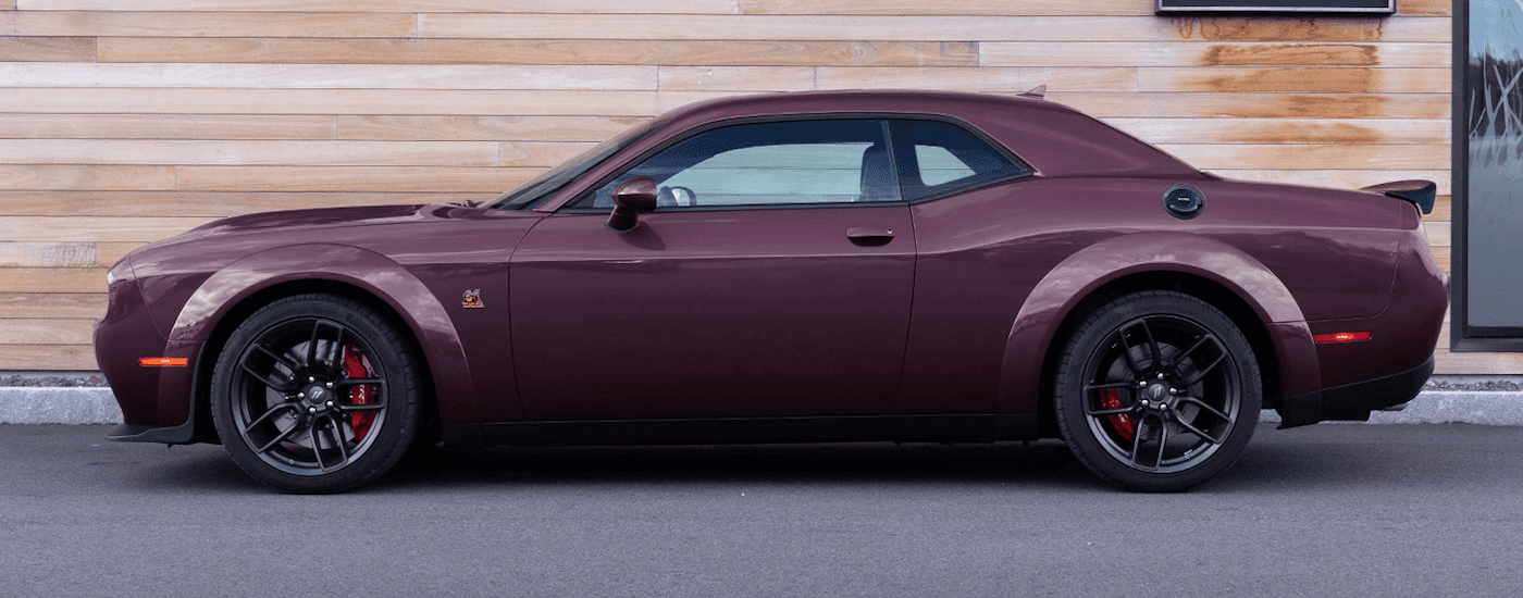 A purple 2022 Dodge Challenger R/T Scat Pack is shown from the side parked in front of a wooden wall.