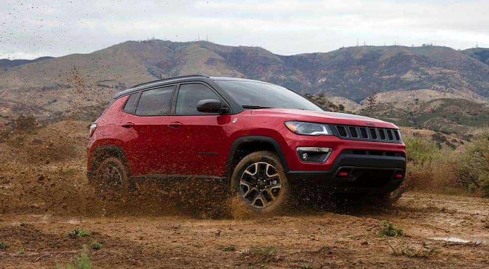 A red 2022 Jeep Compass Trailhawk is shown from the front at an angle while driving off-road.