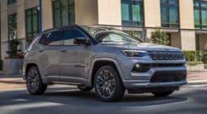 A grey 2022 Jeep Compass is shown driving through a city.
