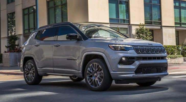 A grey 2022 Jeep Compass is shown driving through a city.