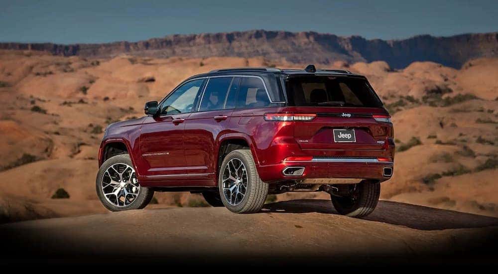 A red 2022 Jeep Grand Cherokee is shown from the rear at an angle while parked off-road.