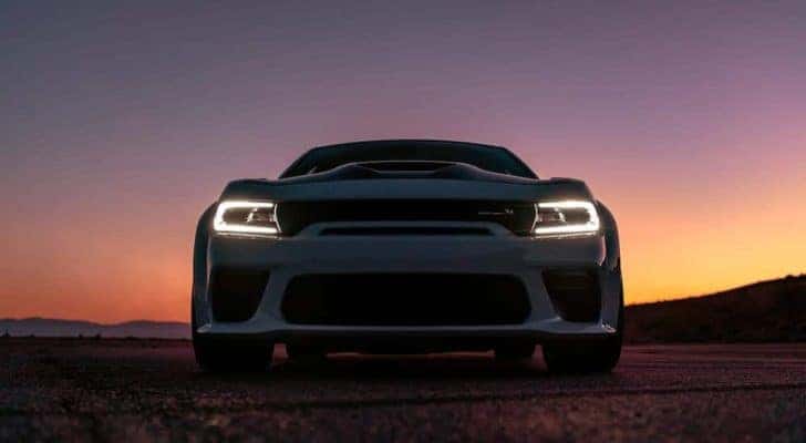 A white 2020 Dodge Charger Scat Pack is shown from a low angle at sunset.