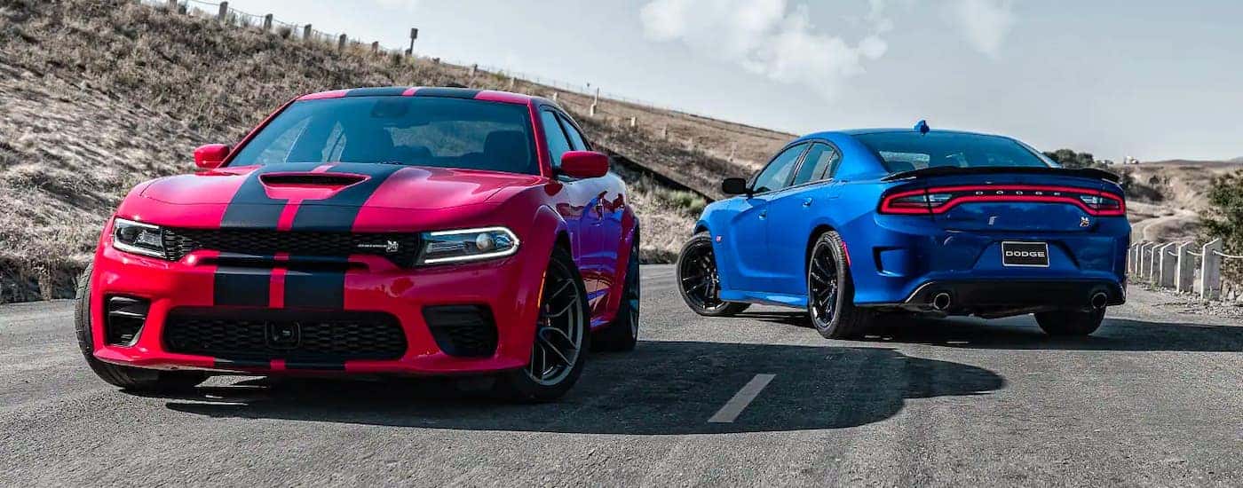 A red and a blue 2021 Dodge Charger Scat Pack are shown parked on a deserted street.