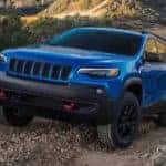A blue 2023 Jeep Cherokee TrailHawk is shown from the front while climbing a hill.