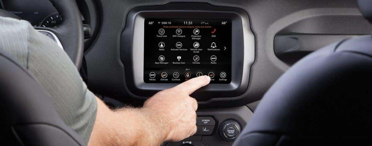 A person is shown interacting with the infotainment screen of a 2023 Jeep Renegade.