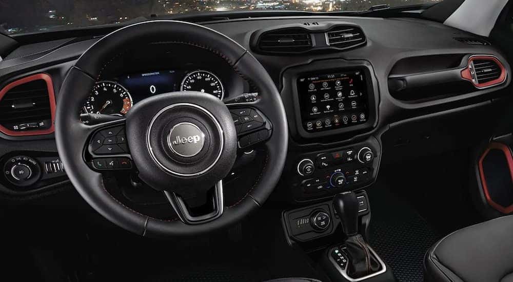 The black interior of a 2023 Jeep Renegade shows the steering wheel and infotainment screen.