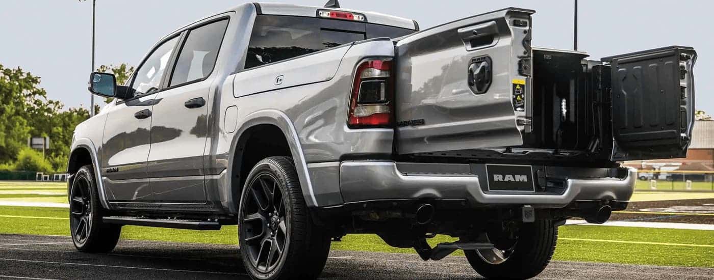 A silver 2023 Ram 1500 is shown from the rear with the rear gate open.