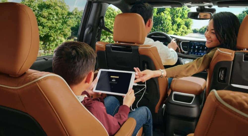 A family is shown inside of a 2023 Chrysler Pacifica with a tan interior.