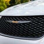 A close up of the hood of a white 2023 Chrysler Pacifica for sale is shown.