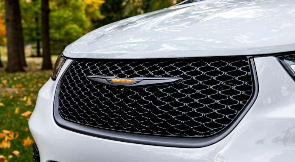 A close up of the hood of a white 2023 Chrysler Pacifica for sale is shown.