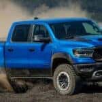 A blue 2023 Ram 1500 TRX is shown off-roading on a dirt area.
