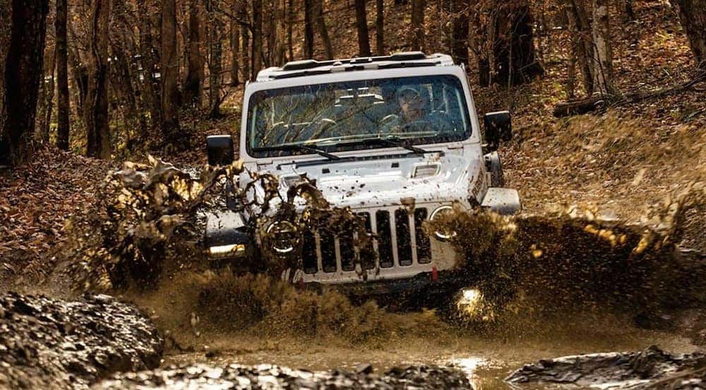 A white 2021 Jeep Wrangler Rubicon is shown off-roading through the mud.