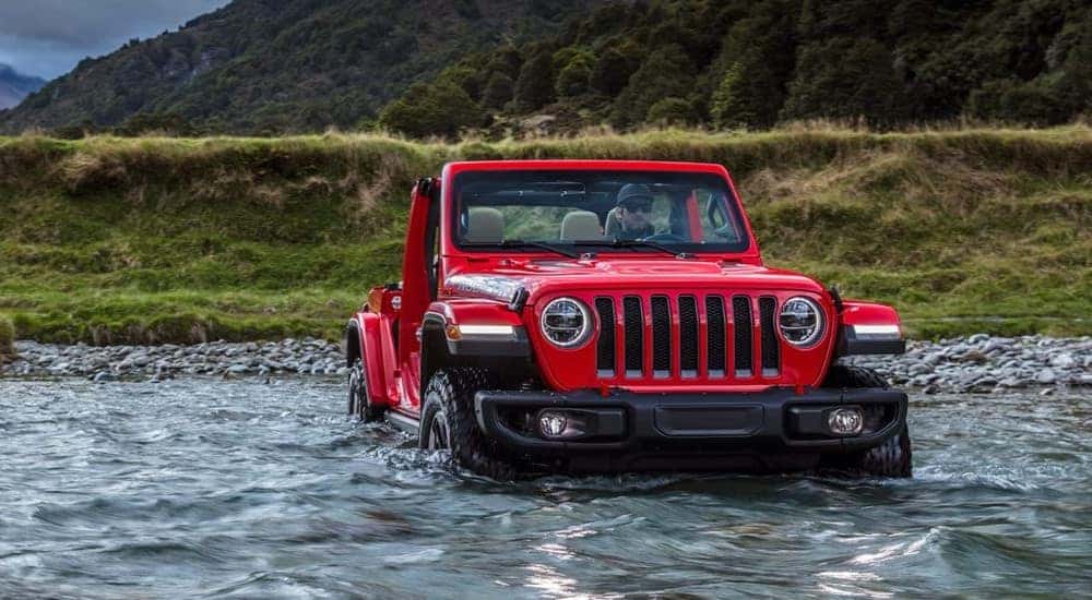 A red 2023 Jeep Wrangler Rubicon is shown driving through the water.