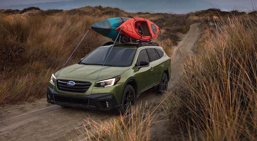 A green 2022 Subaru Outback is shown driving down dirt path.
