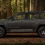 A grey 2023 Grand Cherokee is shown from the side parked in the forest.