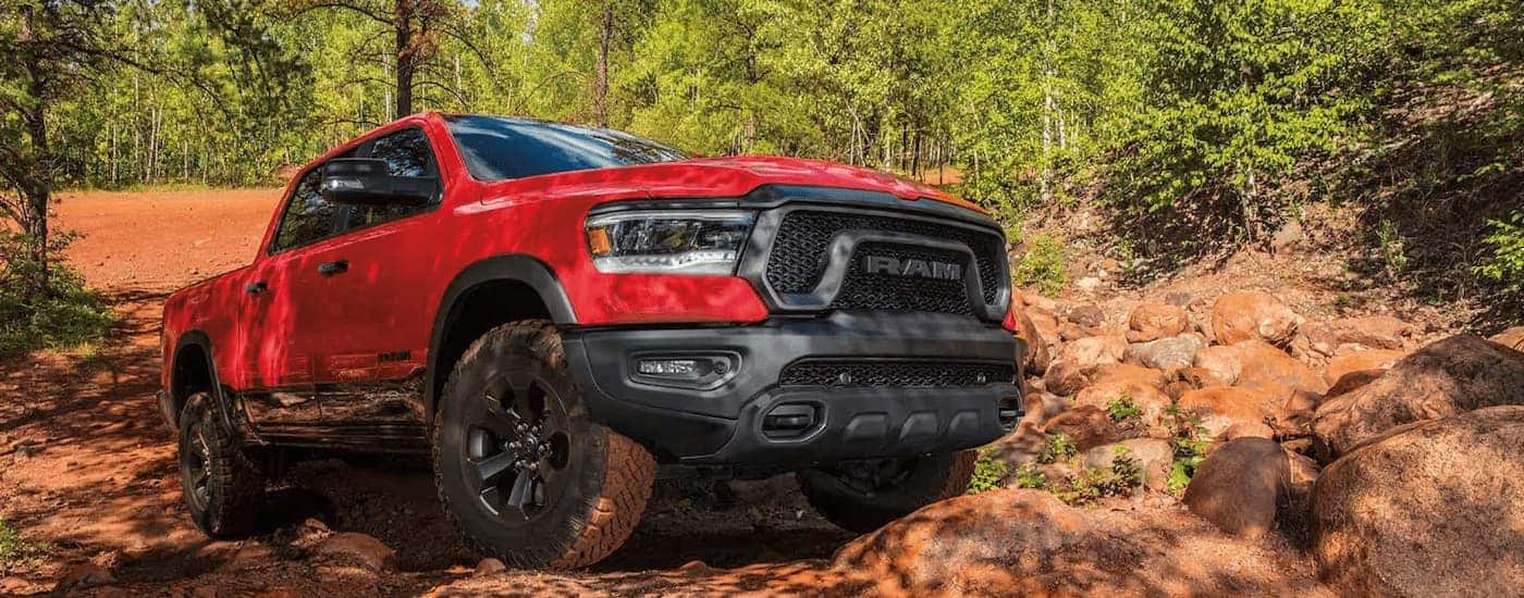 A red 2023 Ram 1500 Rebel is shown off-roading on a dirt trail.