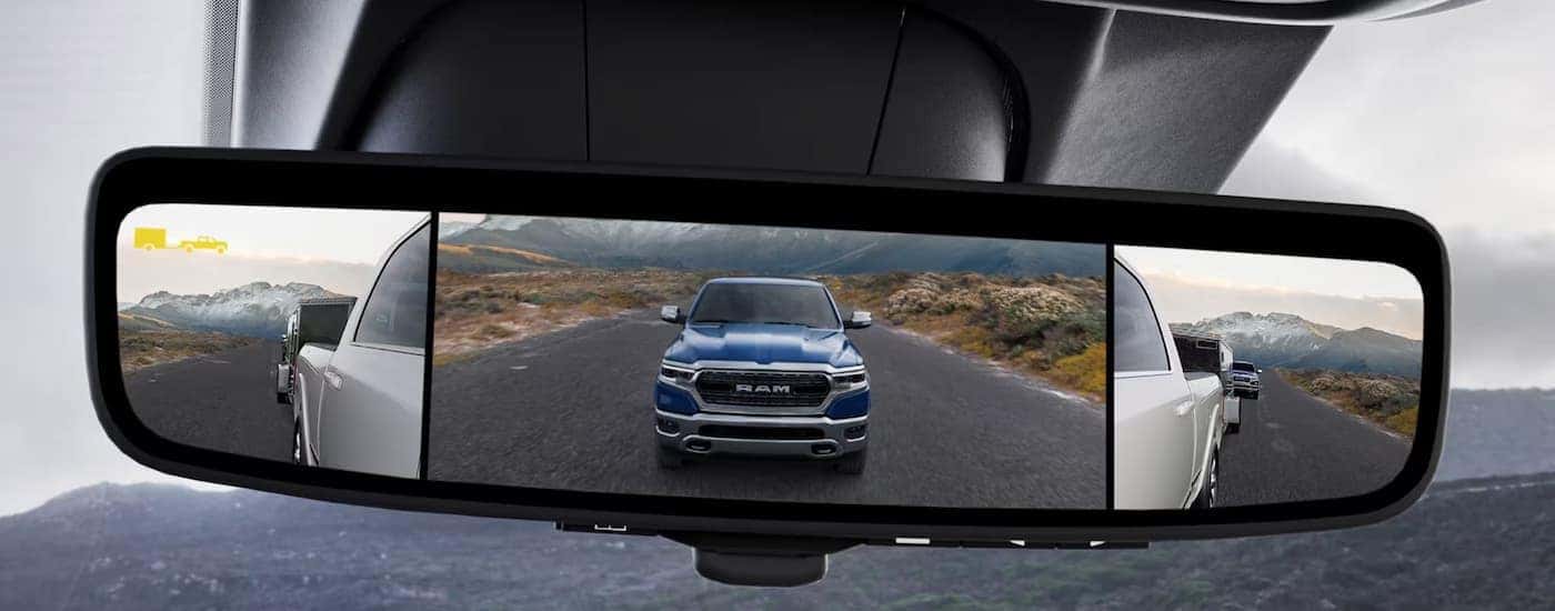 A blue 2023 Ram 2500 is shown in the rearview mirror of a silver 2023 Ram 2500.