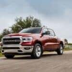 A red 2023 Ram 1500 is shown driving on a road.